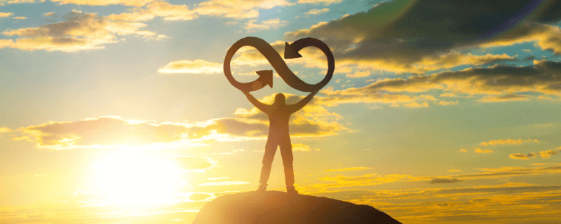man standing on top of a hill holding the circular economy symbol