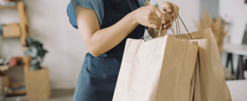 a shop assistant holding paper shopping bags