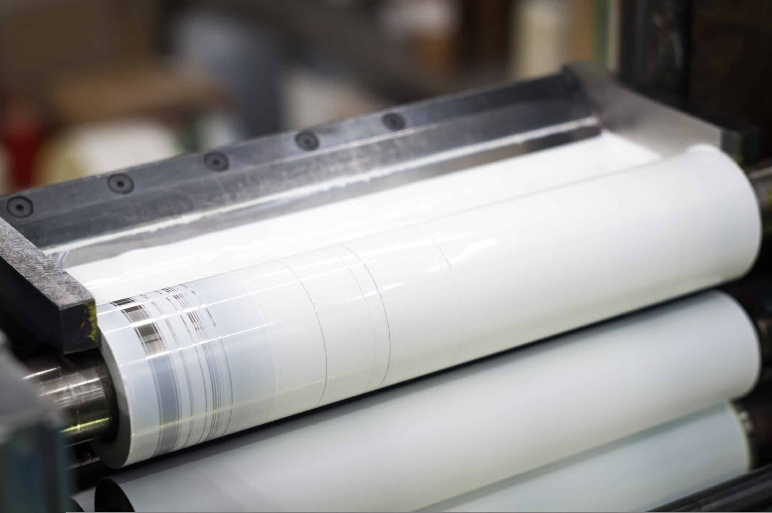 White ink in the ink system of a modern flexographic printing press in a print shop, shown in close-up with selective focus.